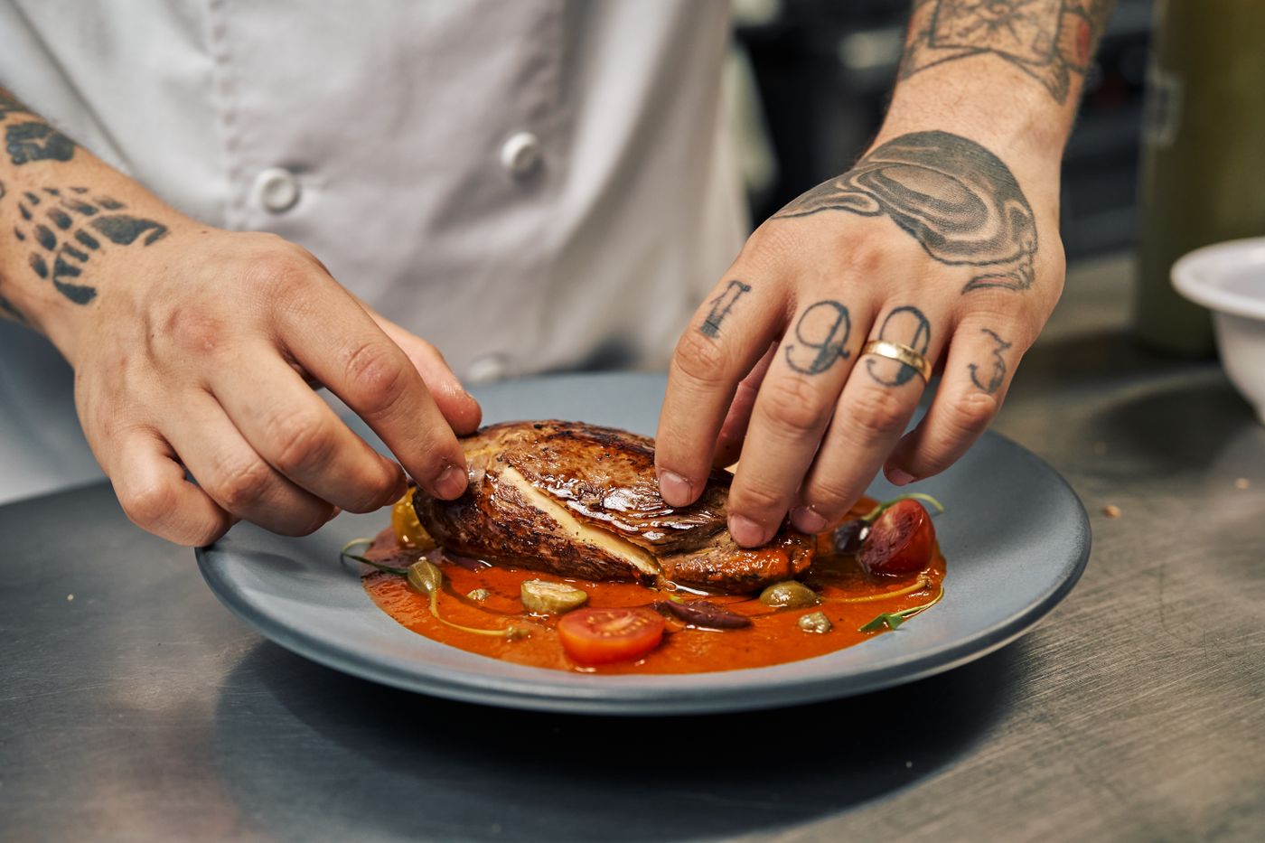 A chef plating a dish in a restaurant kitchen, the operational moment that a review is really describing